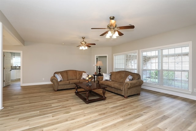 living room featuring ceiling fan, sink, and light wood-type flooring