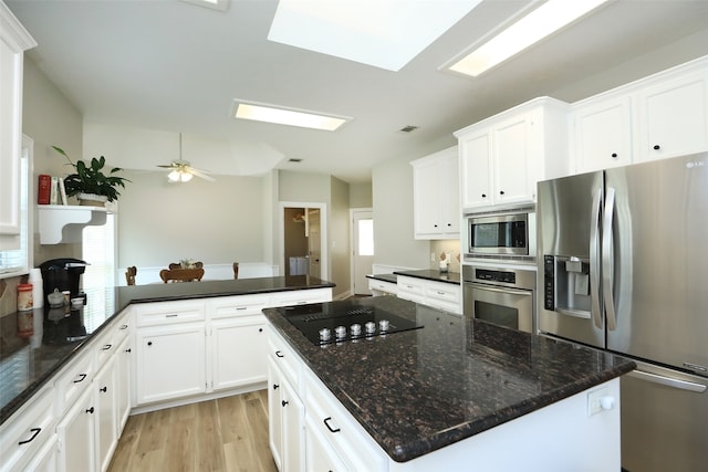 kitchen with dark stone countertops, appliances with stainless steel finishes, ceiling fan, light hardwood / wood-style flooring, and a center island