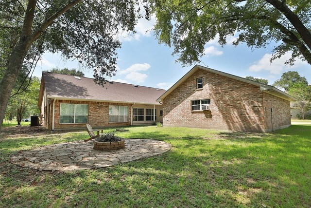 rear view of house featuring central AC, a fire pit, a patio area, and a yard