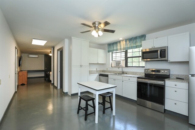 kitchen with appliances with stainless steel finishes, white cabinets, ceiling fan, sink, and light stone counters