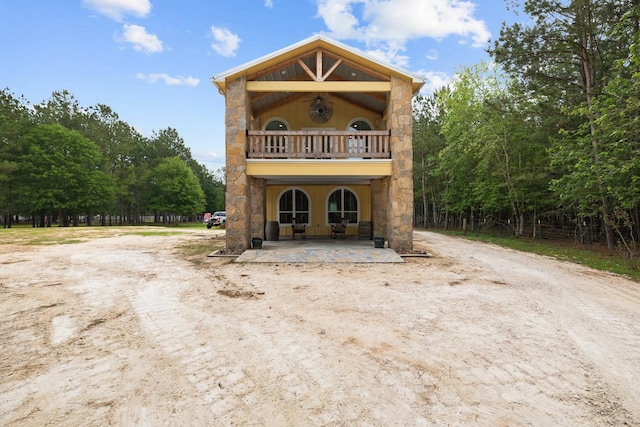 view of front of home featuring stone siding and a balcony