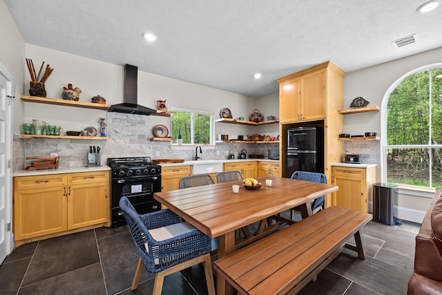 tiled dining area with a textured ceiling, sink, and a healthy amount of sunlight