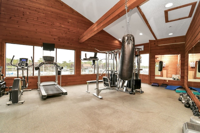 exercise room with wood walls, high vaulted ceiling, and light colored carpet