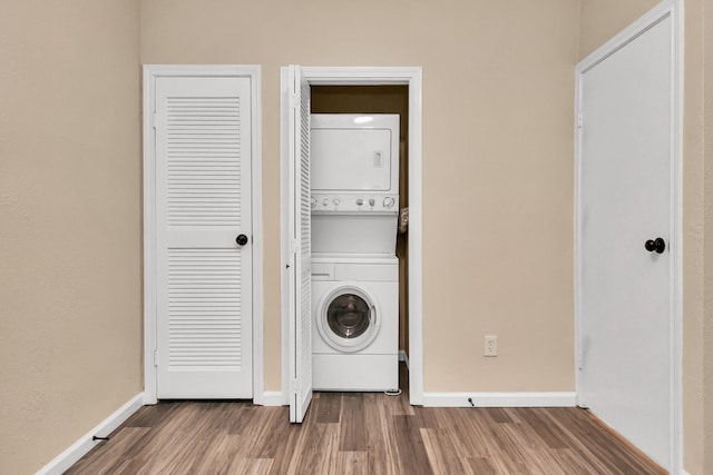 washroom with wood-type flooring and stacked washer and clothes dryer