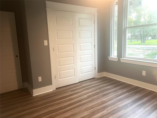 unfurnished bedroom with dark hardwood / wood-style floors and a closet