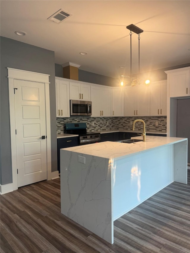 kitchen with hanging light fixtures, appliances with stainless steel finishes, sink, and a center island with sink