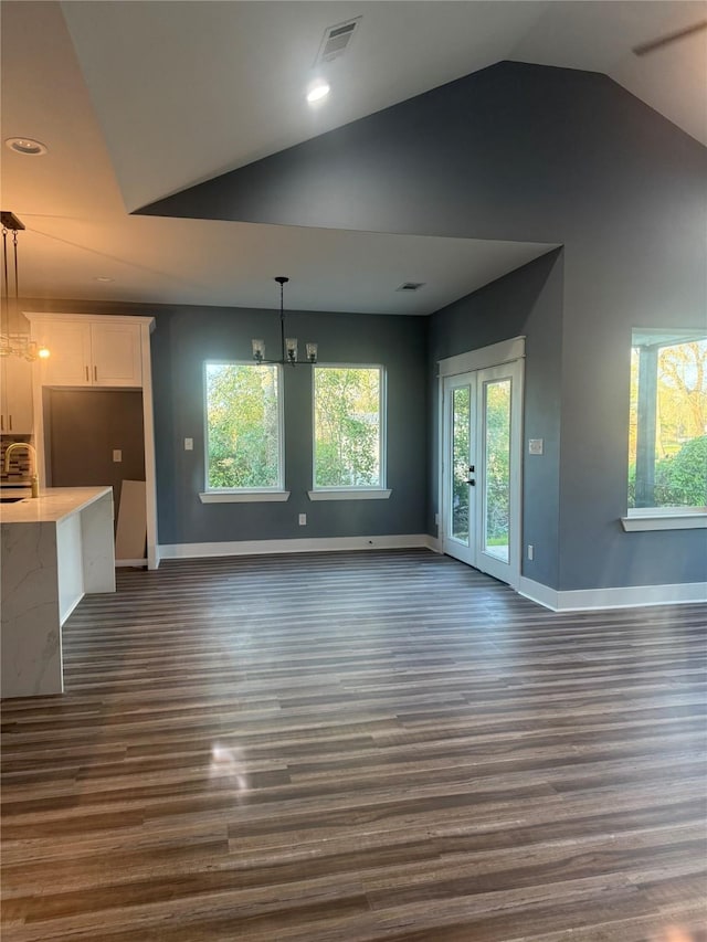 unfurnished living room with lofted ceiling, a notable chandelier, and dark hardwood / wood-style flooring