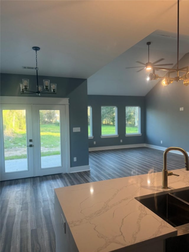 kitchen featuring french doors, sink, pendant lighting, light stone countertops, and ceiling fan with notable chandelier