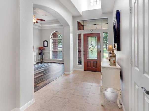 foyer featuring light hardwood / wood-style flooring, a tray ceiling, ceiling fan, and a high ceiling