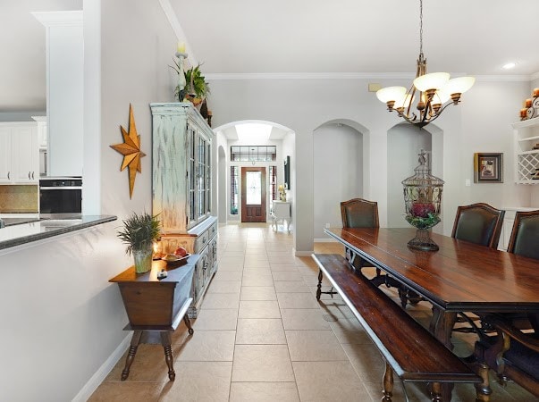 dining area with light tile patterned flooring, a chandelier, and crown molding