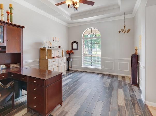 office area featuring crown molding, wood-type flooring, a raised ceiling, and ceiling fan with notable chandelier