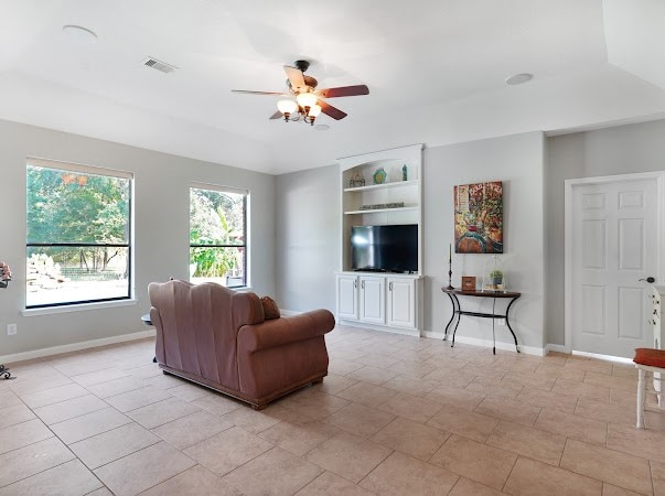 tiled living room featuring ceiling fan and built in shelves