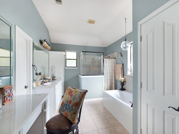 bathroom with plus walk in shower, vanity, vaulted ceiling, and tile patterned flooring