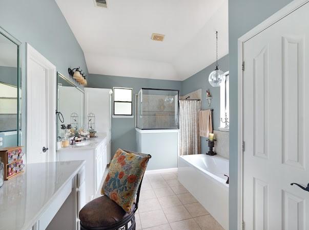 bathroom with tile patterned flooring, vanity, plus walk in shower, and an inviting chandelier