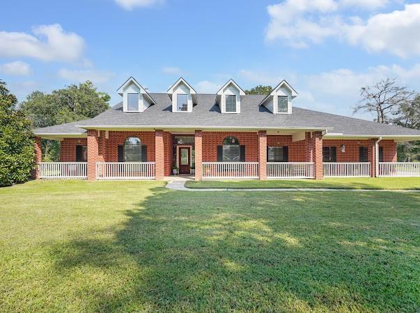 cape cod house with a front yard and covered porch