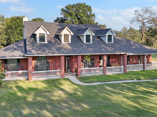 cape cod house with a front lawn and covered porch