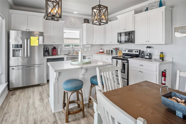 kitchen with appliances with stainless steel finishes, light hardwood / wood-style flooring, decorative light fixtures, white cabinetry, and a kitchen island