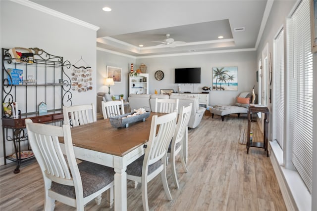 dining area with ceiling fan, crown molding, light hardwood / wood-style flooring, and a tray ceiling