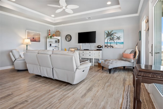 living room with a tray ceiling, light hardwood / wood-style flooring, ceiling fan, and ornamental molding