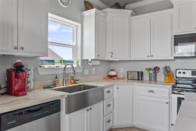 kitchen with white cabinets, sink, appliances with stainless steel finishes, and light stone countertops