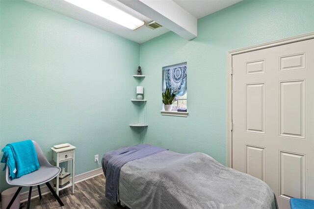 bedroom with beamed ceiling and dark hardwood / wood-style floors