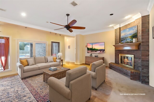 living room featuring crown molding, light hardwood / wood-style floors, a brick fireplace, ceiling fan, and brick wall