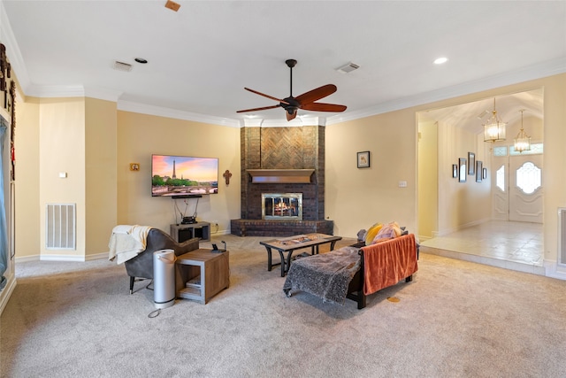 carpeted living room featuring a brick fireplace, ceiling fan with notable chandelier, and crown molding