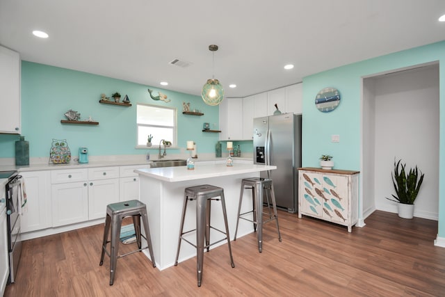 kitchen with appliances with stainless steel finishes, sink, a center island, white cabinetry, and hanging light fixtures