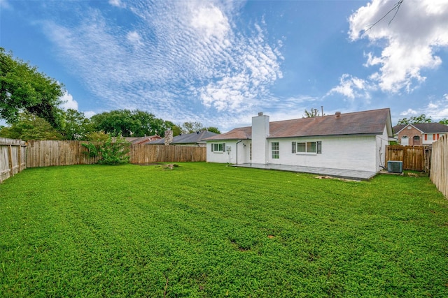 rear view of property with cooling unit and a lawn