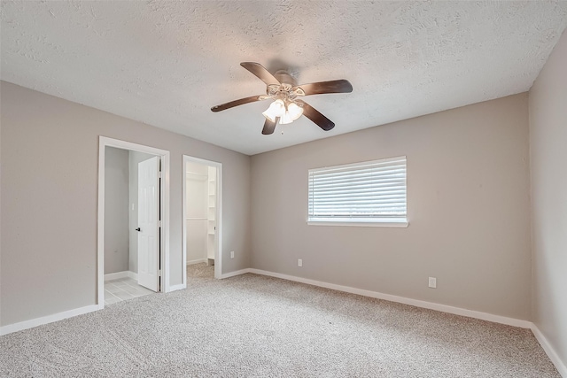 unfurnished bedroom with a spacious closet, a textured ceiling, light carpet, a closet, and ceiling fan