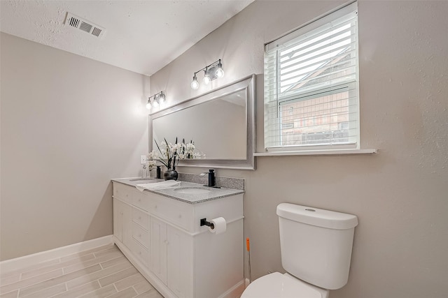 bathroom with a textured ceiling, toilet, and vanity