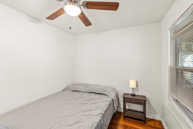 bedroom with ceiling fan, dark wood-type flooring, and a textured ceiling