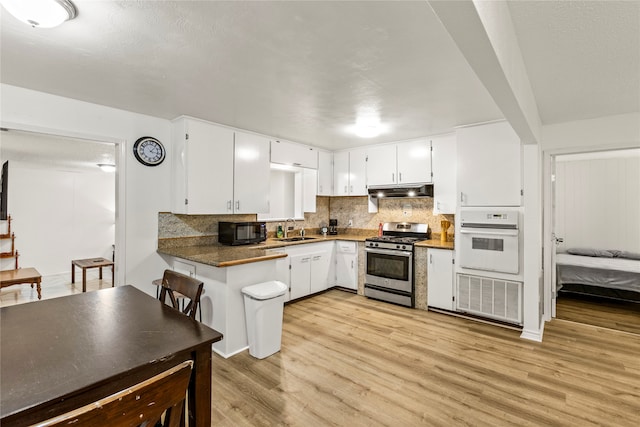 kitchen featuring white cabinetry, oven, light hardwood / wood-style flooring, sink, and stainless steel gas range oven