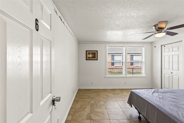 tiled bedroom featuring ceiling fan and a textured ceiling