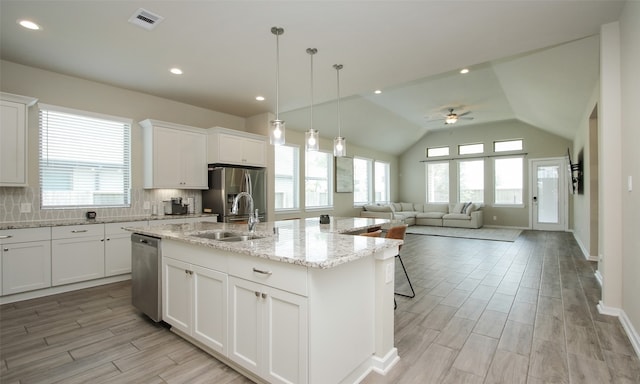 kitchen featuring ceiling fan, stainless steel appliances, a kitchen island with sink, tasteful backsplash, and sink