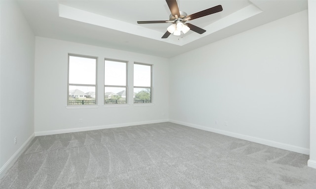 carpeted spare room featuring a raised ceiling and ceiling fan