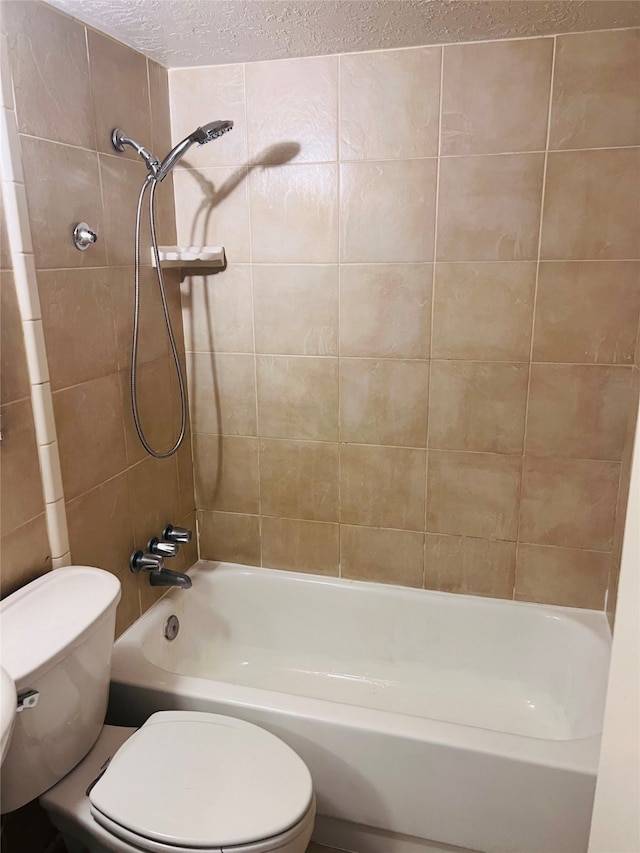 bathroom with tiled shower / bath combo, a textured ceiling, and toilet