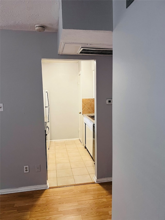 kitchen featuring light hardwood / wood-style flooring, decorative backsplash, and a textured ceiling