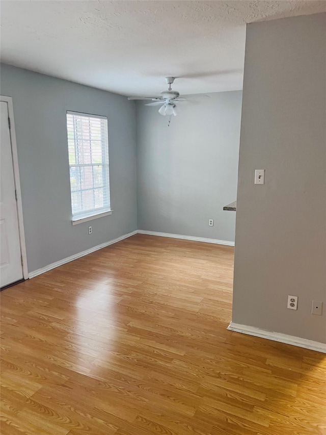 empty room with light hardwood / wood-style flooring, a textured ceiling, and ceiling fan