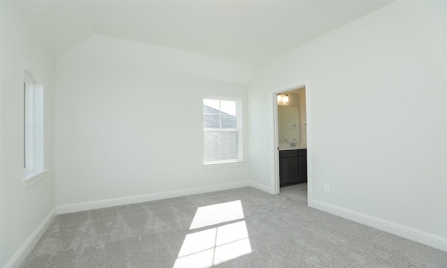 carpeted empty room featuring vaulted ceiling