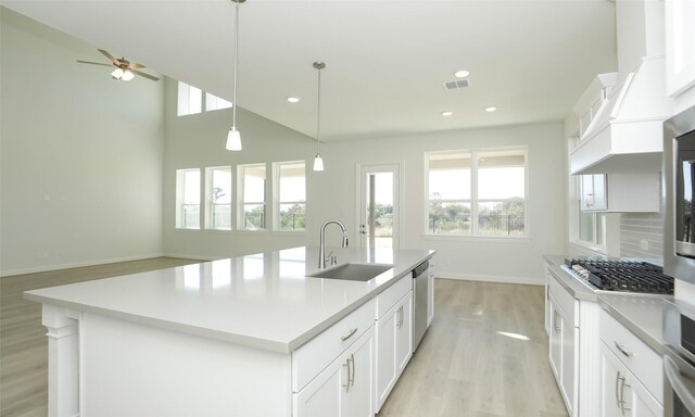 kitchen featuring stainless steel appliances, a kitchen island with sink, sink, decorative light fixtures, and white cabinets