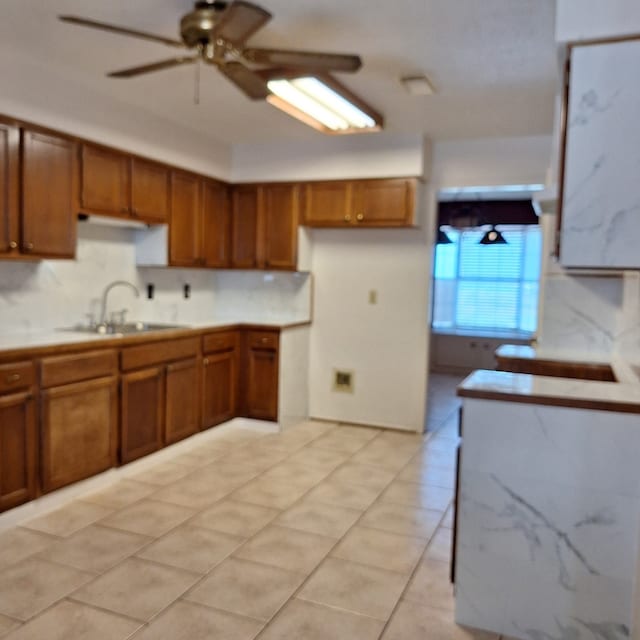 kitchen with backsplash, ceiling fan, sink, and light tile patterned floors