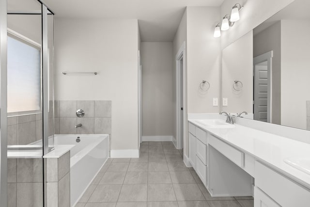 bathroom featuring a relaxing tiled tub, vanity, and tile patterned floors