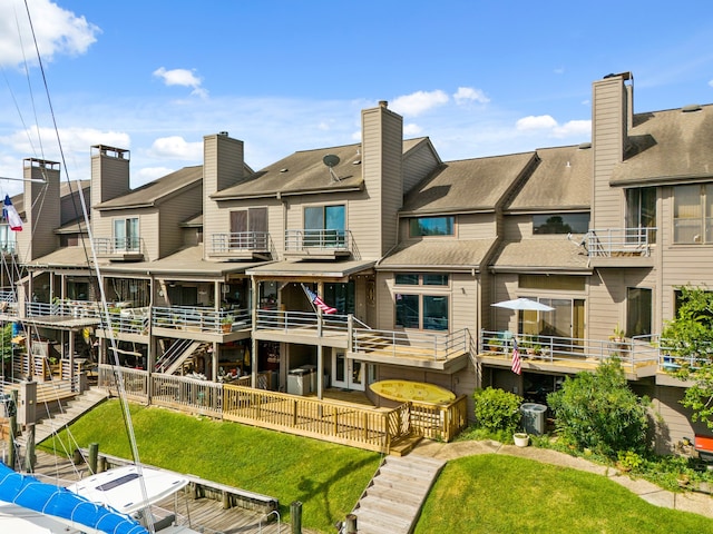 rear view of house with a balcony and a yard