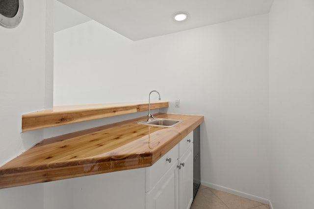 interior space with butcher block counters, sink, light tile patterned floors, and white cabinets