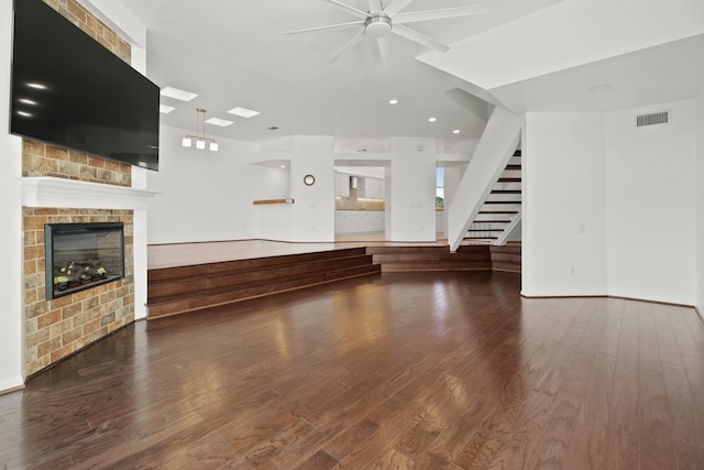 unfurnished living room with hardwood / wood-style floors, a brick fireplace, and ceiling fan