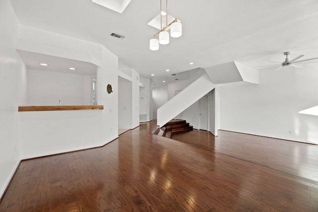 unfurnished living room featuring dark wood-type flooring, a skylight, and ceiling fan