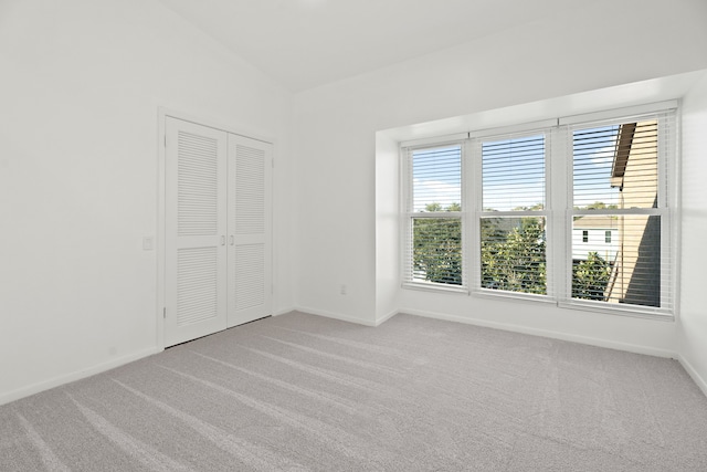 unfurnished room with lofted ceiling and light carpet