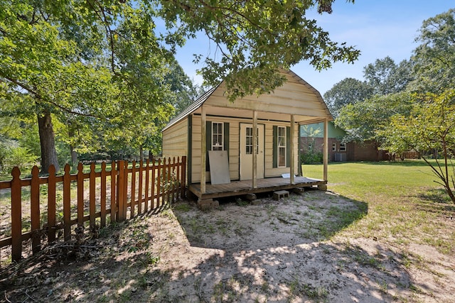 view of front of home with a front yard, an outdoor structure, and a wooden deck