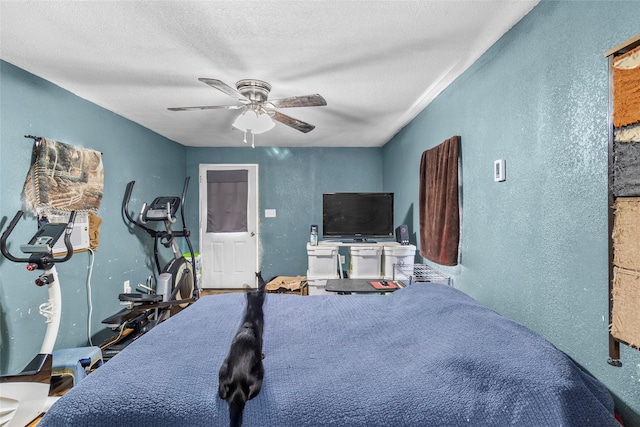 bedroom with a textured ceiling, a textured wall, and a ceiling fan